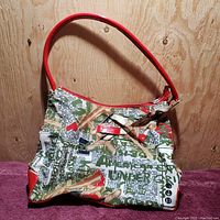 Full front view of the Matt & Nat Montreal hand bag showing the printed fabric exterior and red handle and trim.
