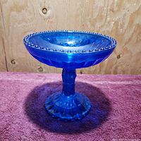 Side view of the vintage Fenton diamond glass candy dish showing its tapering stem and bead-rimmed bowl.