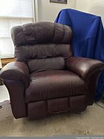Front view of oversized brown leather La-Z-Boy recliner chair showing padded armrests and cushioned backrest.