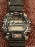 Front close-up of the Casio G-Shock watch showing the digital face, buttons, and wear on the resin band and case.