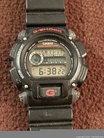 Front view of Casio G-Shock DW-9052 watch showing digital display, buttons, markings and strap.