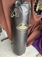 Full frontal view of the Century branded punching bag showing durable black synthetic leather exterior and attached hanging chain.