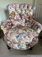 Front view of over stuffed floral pattern accent chair showing detailed upholstery and tufted back.