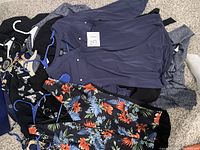View of assorted blouses laid out showing a variety of colors and patterns including navy, floral, grey, and black.