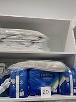 Top shelf showing stacked white disposable bed chux pads wrapped in plastic