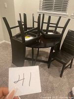 Round dark brown/black kitchen table with four chairs on top and around it, showing overall set condition and style.