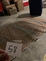 Photo showing the full large hand woven area rug laid flat on the floor, highlighting the mandala pattern and color scheme.