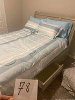 Front left angle of painted wood bed frame showing curved headboard and open left storage drawer
