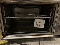 Open interior view of the Power XL oven air fryer showing the wire rack and multiple metal skewers inside, with a paper label '59'.