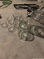 Photo showing all glass jars and bowls on a concrete floor with a tag marked 61