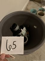 Top view inside large dark gray plant pot containing smaller pots and gardening items.