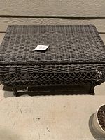Top-down view of closed square wicker table with label on top.