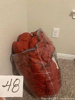 Red king size comforter packed in clear plastic bag, showing red color and stitched pattern.