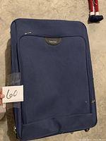 Front view of large blue suitcase with front pocket and Calvin Klein tag