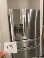 Front view of stainless steel refrigerator showing French doors and water dispenser.