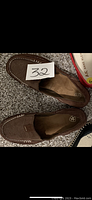A top-down view of the pair of brown Ariat flat walking shoes on carpet with a paper label showing number 32.