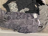 Three cardigans laid flat showing knit patterns and textures
