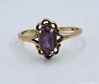 Front view of the gold ring featuring an oval marquise amethyst with detailed openwork around the stone.