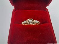 Front view of vintage 10K gold engagement ring showing the central diamond and side smaller diamonds in a red ring box.