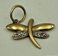 Gold dragonfly charm front showing polished and textured wing design with attached loop.