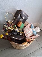 Full view of basket showing porcelain figurine, jewelry box, bottles, and other items inside.
