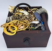 Wooden box filled with mixed vintage and sterling jewelry pieces including bracelets, chains, brooches, and earrings in gold-tone and silver-tone finishes.