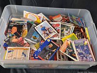 Large transparent plastic bin full of assorted sports cards in mixed condition.