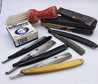 Front angle showing five straight razors, shaving brush, soap, and razor cases