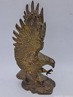 Front view of the metal eagle statue showing the spread wings and detailed feathers with a textured base.