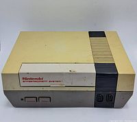 Top and front view of the Nintendo Entertainment System console showing yellowing and surface wear.