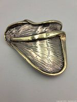 Front view of sterling silver and gold-toned modernist brooch or pendant with detailed textured surface and asymmetrical shape.