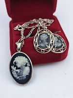 Set of sterling silver cameo necklace and earrings displayed on a red velvet surface