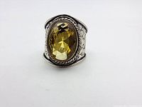 Front view of the ring showing large oval faceted citrine in decorative bezel with twisted rope detail on wide sterling silver band.