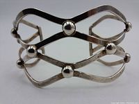 Front side view showing the open lattice silver strips with three spherical accents.