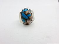Front view of the ring showing the polished turquoise and other stone inlay in an oval shape set in a silver bezel with twisted rope detailing.