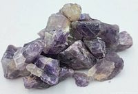 Close-up photo of raw Thunder Bay amethyst crystal pieces showing purple and white coloration, natural rough texture, and crystalline formations.