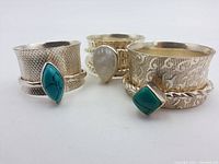 Three sterling silver spinner rings shown from front angle, highlighting stones and band patterns.