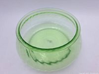 Close-up photo of the uranium glass bowl showing the thick rounded glass rim and translucent green color.