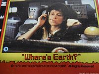 Close-up photo of an Alien trading card featuring a woman with a headset in the pilot's seat with text caption 'Where's Earth?'