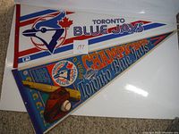 Two triangular Toronto Blue Jays pennants side by side on carpeted floor