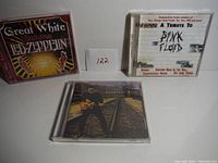 Three CD cases showing titles and cover art for tribute and greatest hits albums.