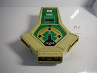 Top-front view showing the triangular game shape, green baseball diamond graphic with scoreboard, Coleco branding on bottom and game buttons on front.