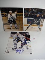 Three autographed photos of Toronto Maple Leafs players Matt Stajan, Sergei Berezin, and Alyn McCauley on ice during hockey games.