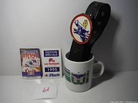 Shows the two Nordiques hockey books standing upright beside the Whalers logo ceramic mug holding the Kansas City Scouts leather belt with logo buckle inside.