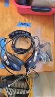 Aircraft Spruce aviation headset with blue ear cups, metal headband, coiled cord, and a two-way microphone. Missing one ear foam.