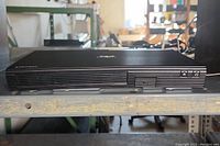 Front view of Samsung BD J5700 CD Player showing slim black casing and vented front panel.