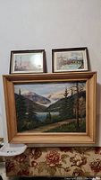 Framed original landscape painting with two smaller framed prints above it