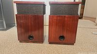 Pair of vintage wooden speakers with fabric grilles shown front view on carpet