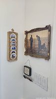 Corner wall displaying the framed antique style print and the vertically hung carved wooden plaque with five small blue and white plates.