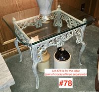 Front and side angle view of square glass topped side table with metal base, showing ornate scrollwork and finish.